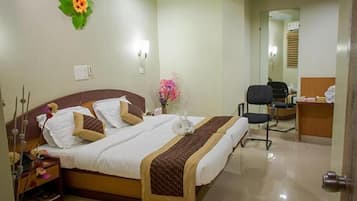 Habitación de hotel con cama, mesita de noche, lámpara y escritorio con silla.