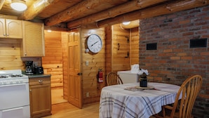 Een houten hut met een keuken, een eethoek en een bakstenen muur.