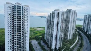 A high-rise residential building complex with multiple floors, a road with vehicles, and a body of water in the background. - Cozy 2B1R 4pax condo Forest City 3A-3202 (Gelang Patah)