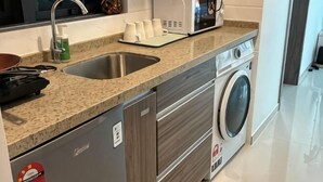 A kitchen with a sink, microwave, and washing machine. - Cozy 2B1R 4pax condo Forest City 3A-3202 (Gelang Patah)