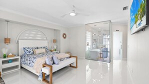 A modern bedroom with a large bed, bedside tables, a ceiling fan, and a glass shower enclosure. - Waterfront Gulf Access Paradise in Marco Island – Pool, Jacuzzi & Game Room Fun! (Marco Island)
