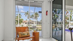 A room with a wicker chair and a small wooden table with a sign that reads "Coffee". - Waterfront Gulf Access Paradise in Marco Island – Pool, Jacuzzi & Game Room Fun! (Marco Island)