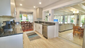 A modern kitchen with a central island, wooden dining table, and a cozy seating area. - Pelicans Landing - 4BR/3BA Home - Heated Pool - - Close to Beach and Historic Downtown (Stuart)