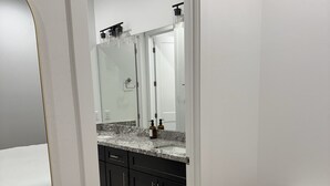 Un baño moderno con un espejo grande, muebles oscuros y una encimera de mármol.