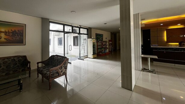 Un hall espacioso con una moderna recepción, un área de descanso con mobiliario estampado y vistas al exterior a través de grandes puertas de vidrio.