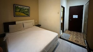Habitación de hotel con cama, un cuadro en la pared, una puerta y un piso estampado.