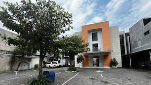 Un patio con pavimento de adoquines, un edificio moderno con fachada de madera y vehículos estacionados.