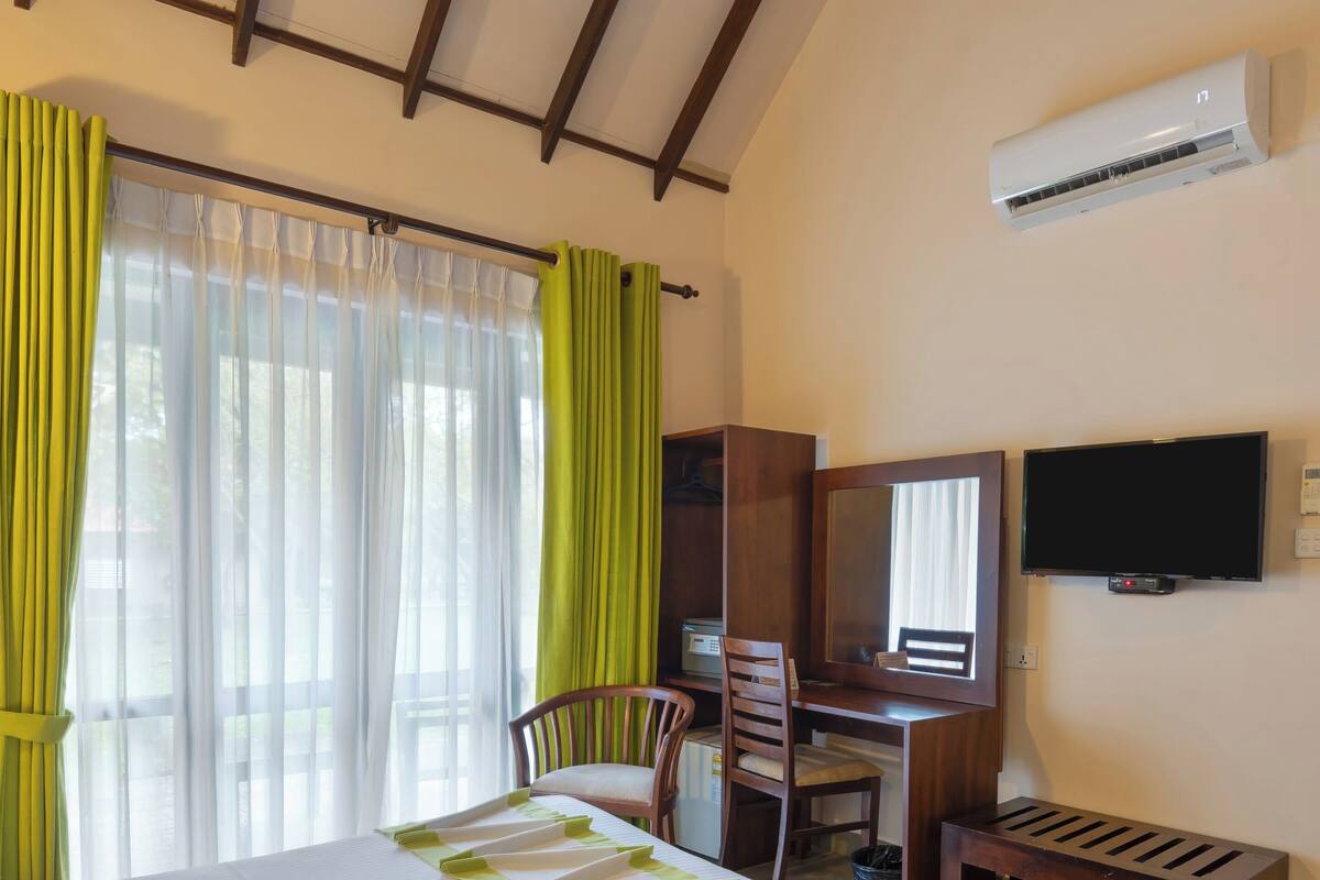 Ein Hotelzimmer mit Bett, Schreibtisch, Stuhl, Fernseher und Klimaanlage.