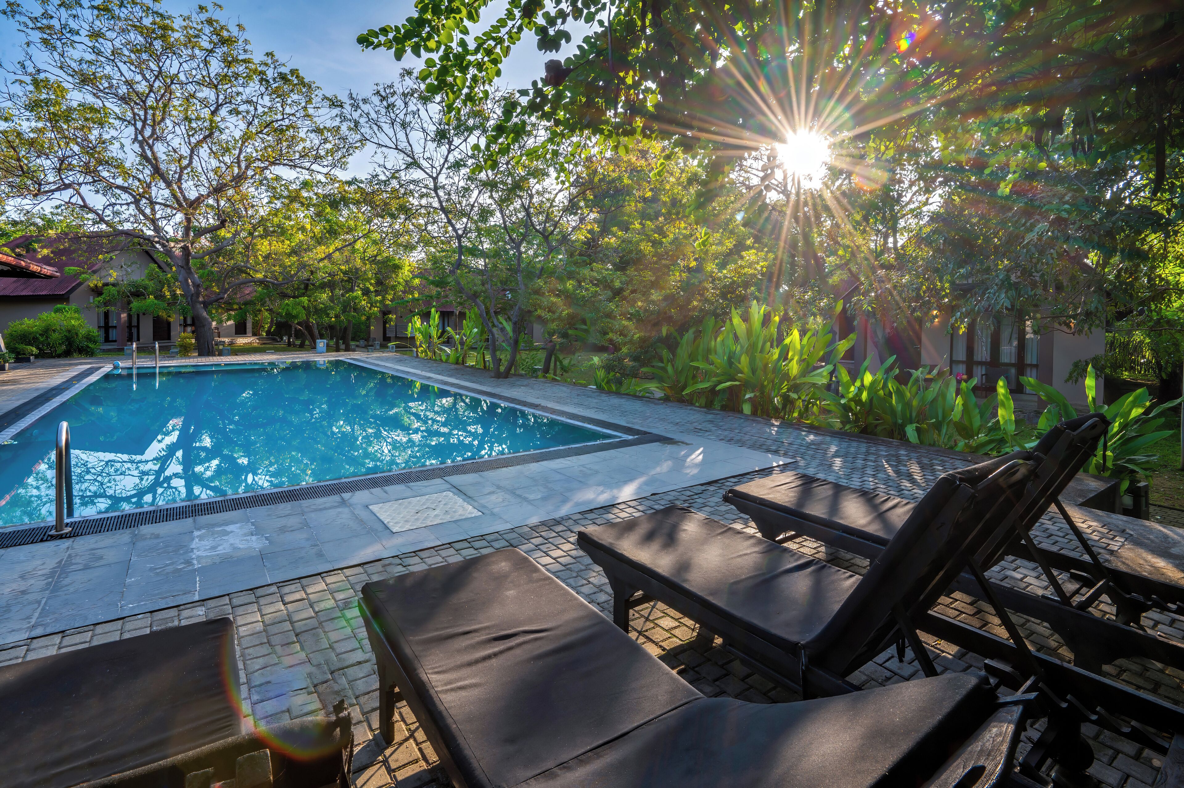 A swimming pool with lounge chairs and a tiled deck.