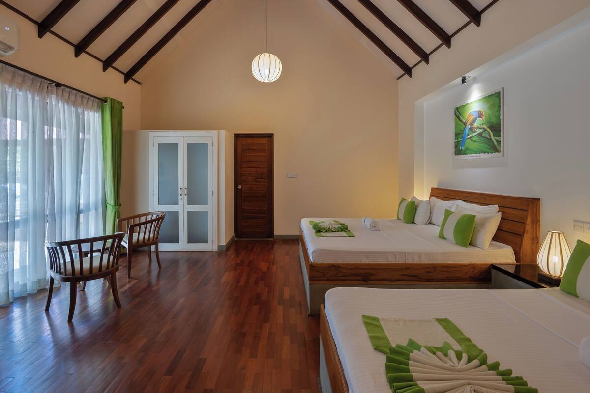 Ein Hotelzimmer mit zwei Betten, einer Holzbalkendecke, einem grünen Vorhang und einer Tür.