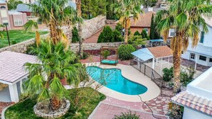 Zona residencial con piscina, palmeras y un muro de piedra.