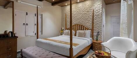 A bedroom with a four-poster bed, a wooden dresser, a bench, a chair, and a small table with fruit.