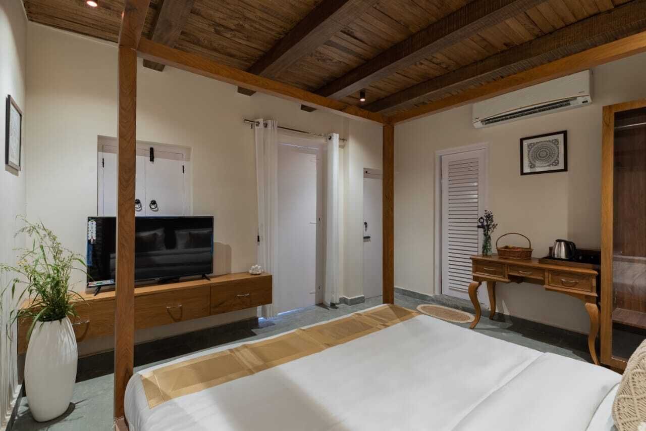Un dormitorio con una cama, televisor, escritorio de madera y una planta.