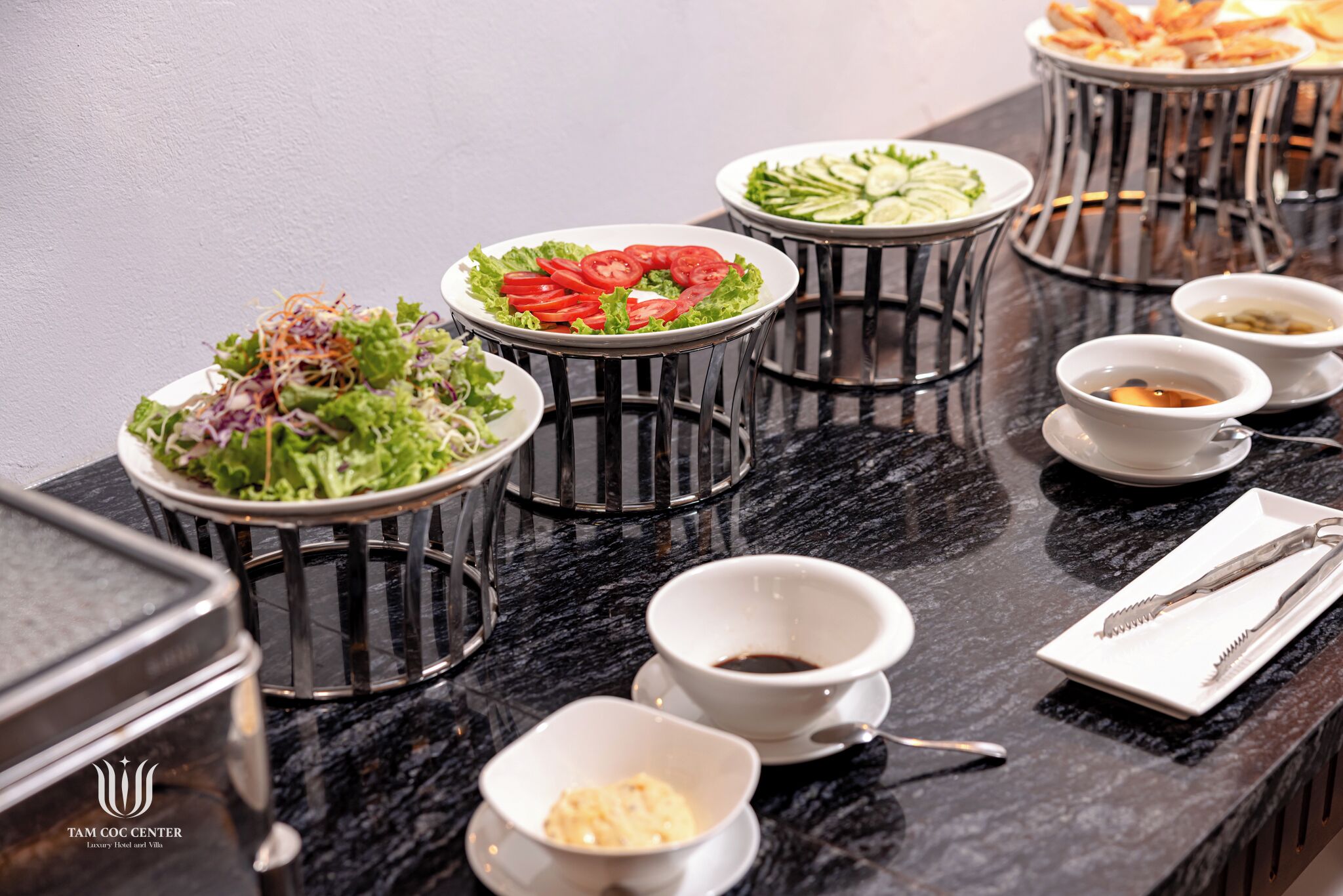 A buffet setup with various dishes and condiments on a marble countertop.