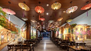 Un restaurante con un largo pasillo, techo de madera y faroles colgantes. Mesas y sillas están dispuestas a lo largo de los lados.