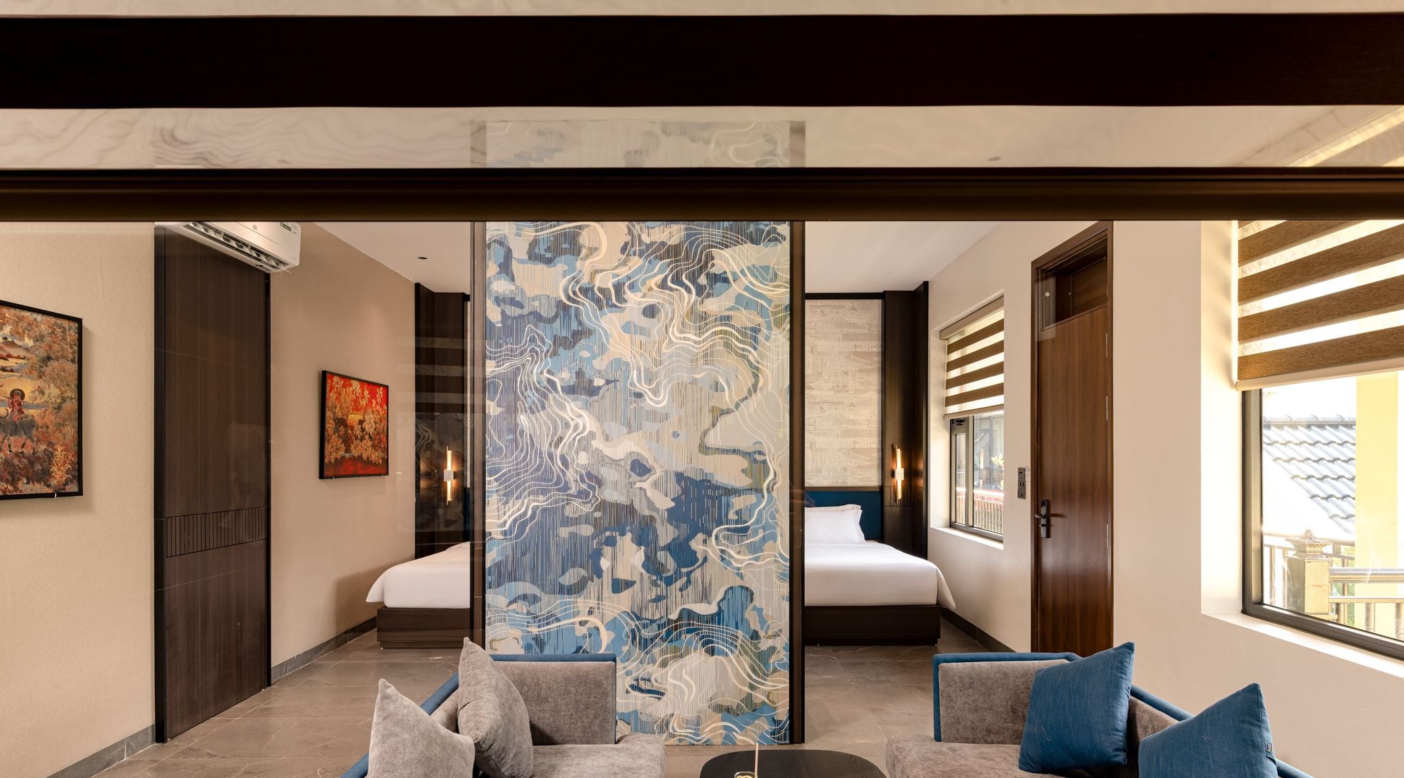 A modern hotel room with a large bed, a seating area with a coffee table, and artwork on the walls.