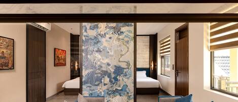 A modern hotel room with a large bed, a seating area with a coffee table, and artwork on the walls.