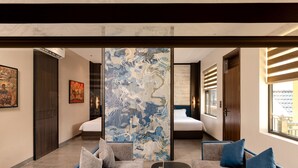 Una habitación de hotel moderna con una cama grande, un sofá, un detalle decorativo en la pared y vistas al exterior.