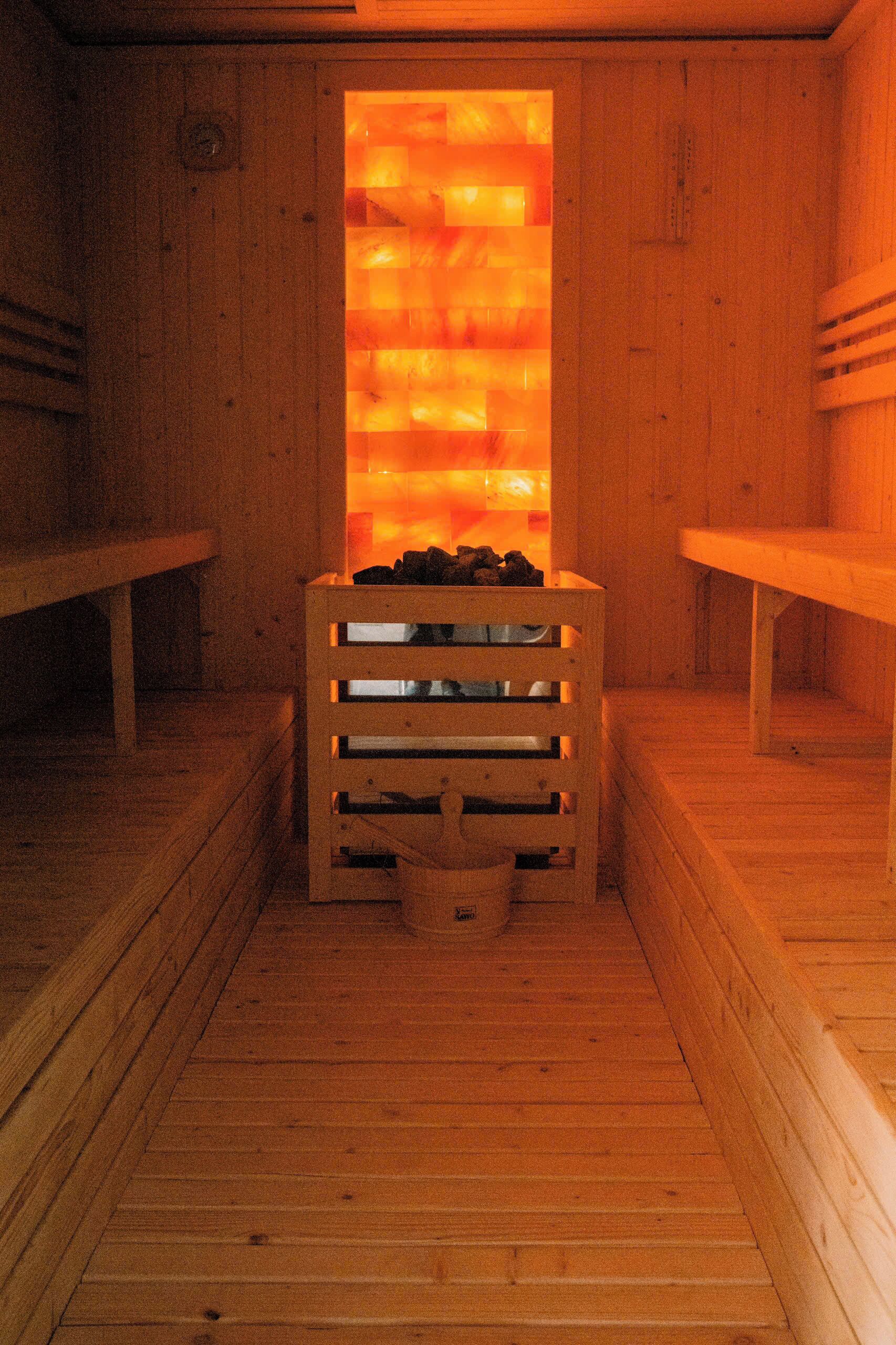 A sauna with wooden benches and a central bench with a heat source.