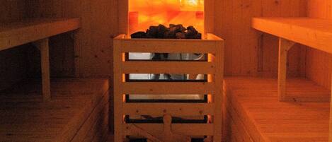 A sauna with wooden benches and a central bench with a heat source.