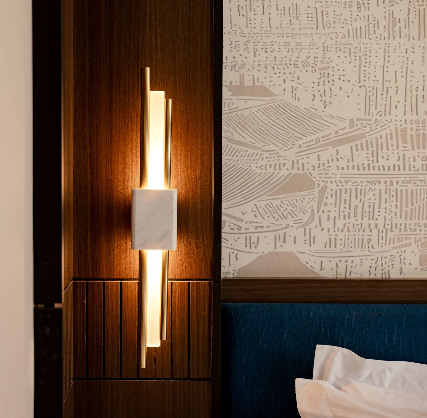 A hotel room with a wooden panel wall, a modern light fixture, and a patterned wallpaper.