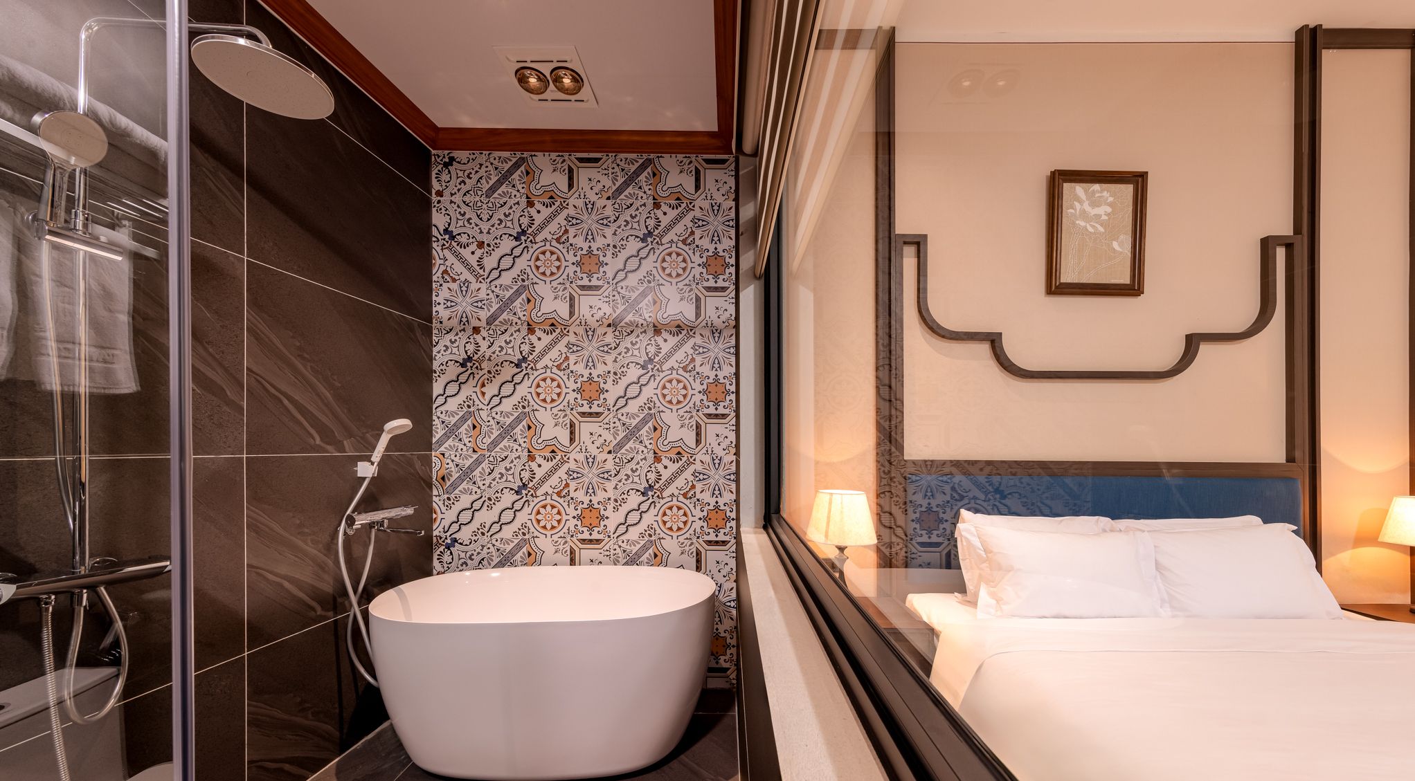 A modern bathroom with a glass-enclosed shower, a freestanding bathtub, and a tiled wall with a decorative pattern.