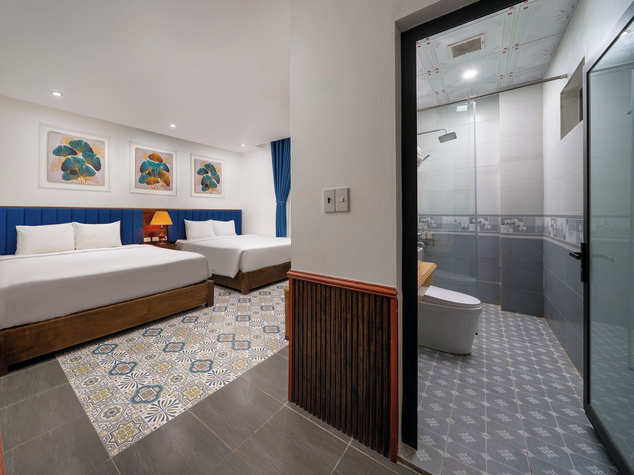 A hotel room with two beds, a bathroom, and a shower area.