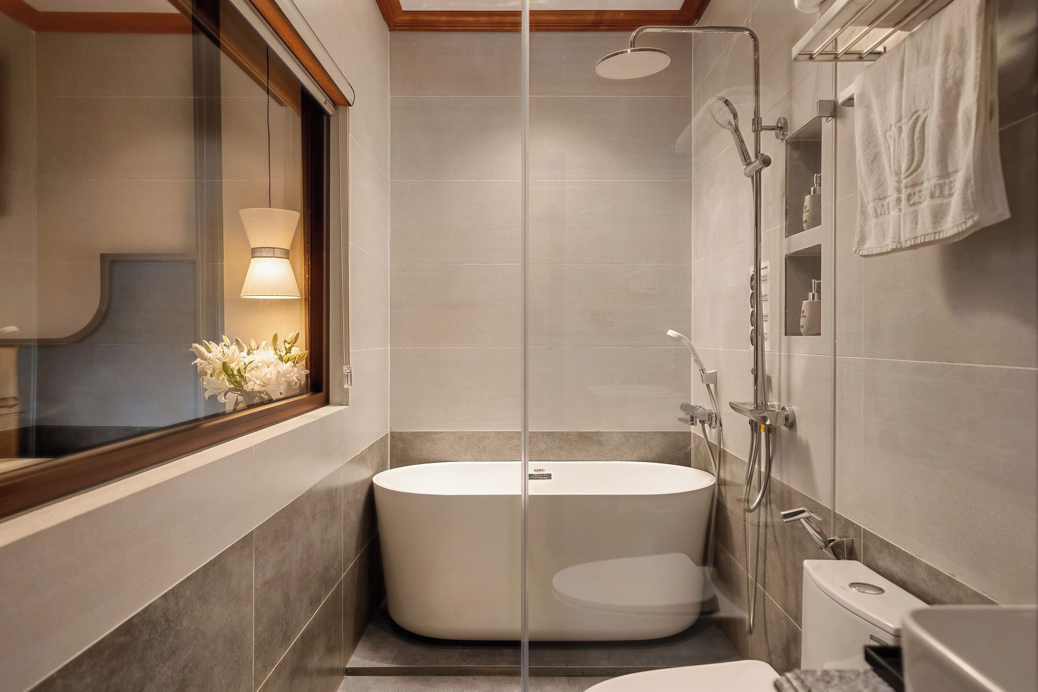 A modern bathroom with a freestanding bathtub, a glass shower enclosure, and a window with a view.