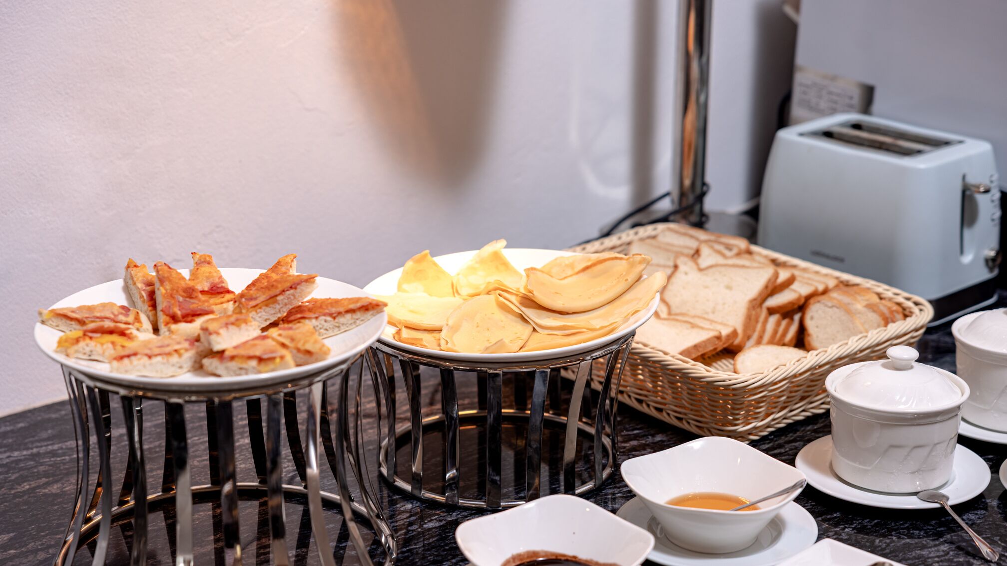 Un bufé de desayuno con diversos pasteles, pan y un tostador.