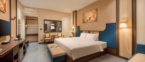 A hotel room with a bed, a desk, a chair, a TV, and a painting on the wall.