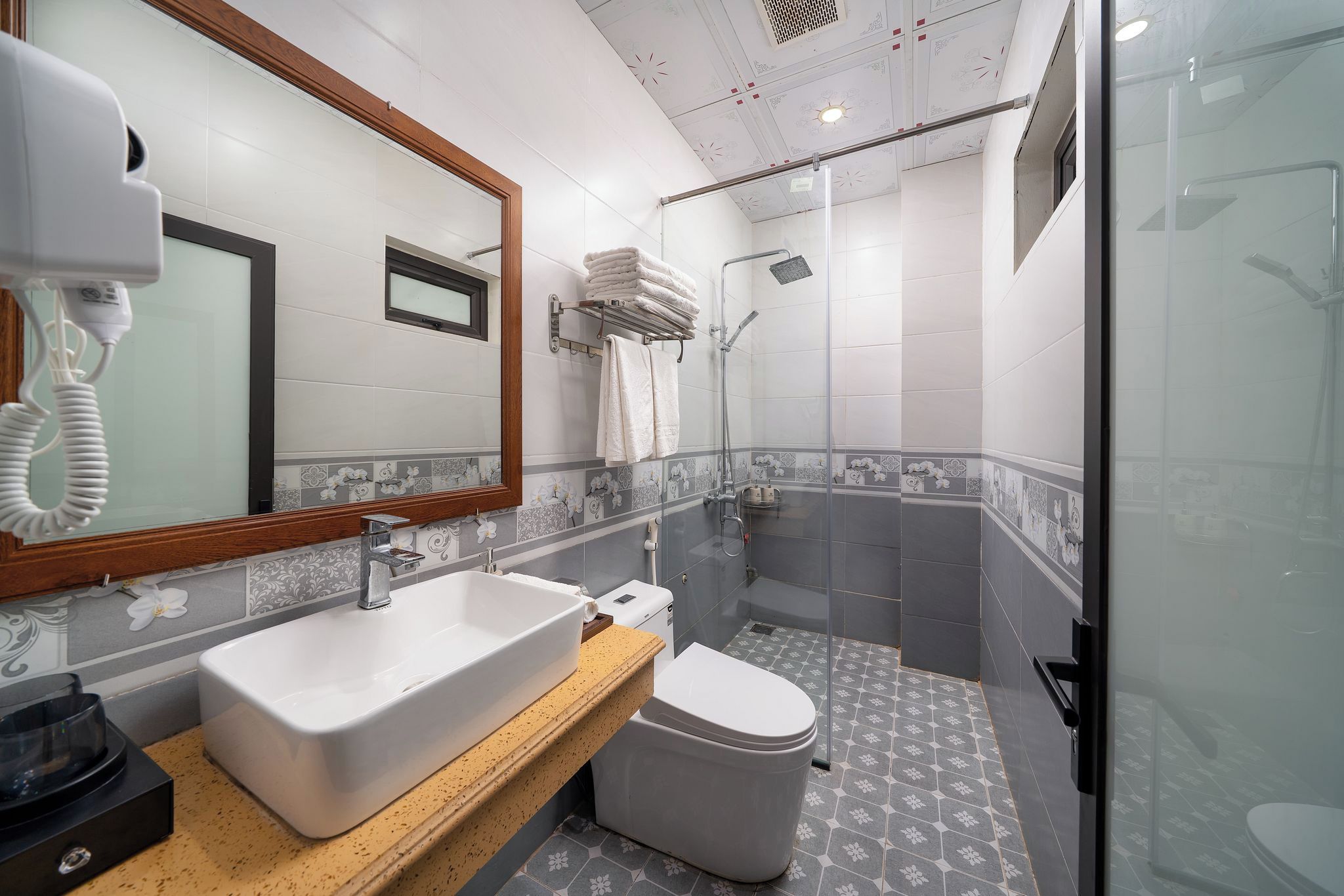 A modern bathroom with a large mirror, a sink, a toilet, and a shower area.