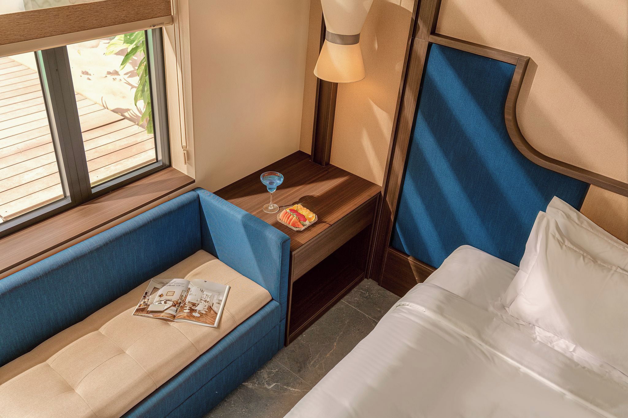 Habitación de hotel pequeña con cama, un área de descanso, una ventana y una mesa con lámpara y un plato de comida.