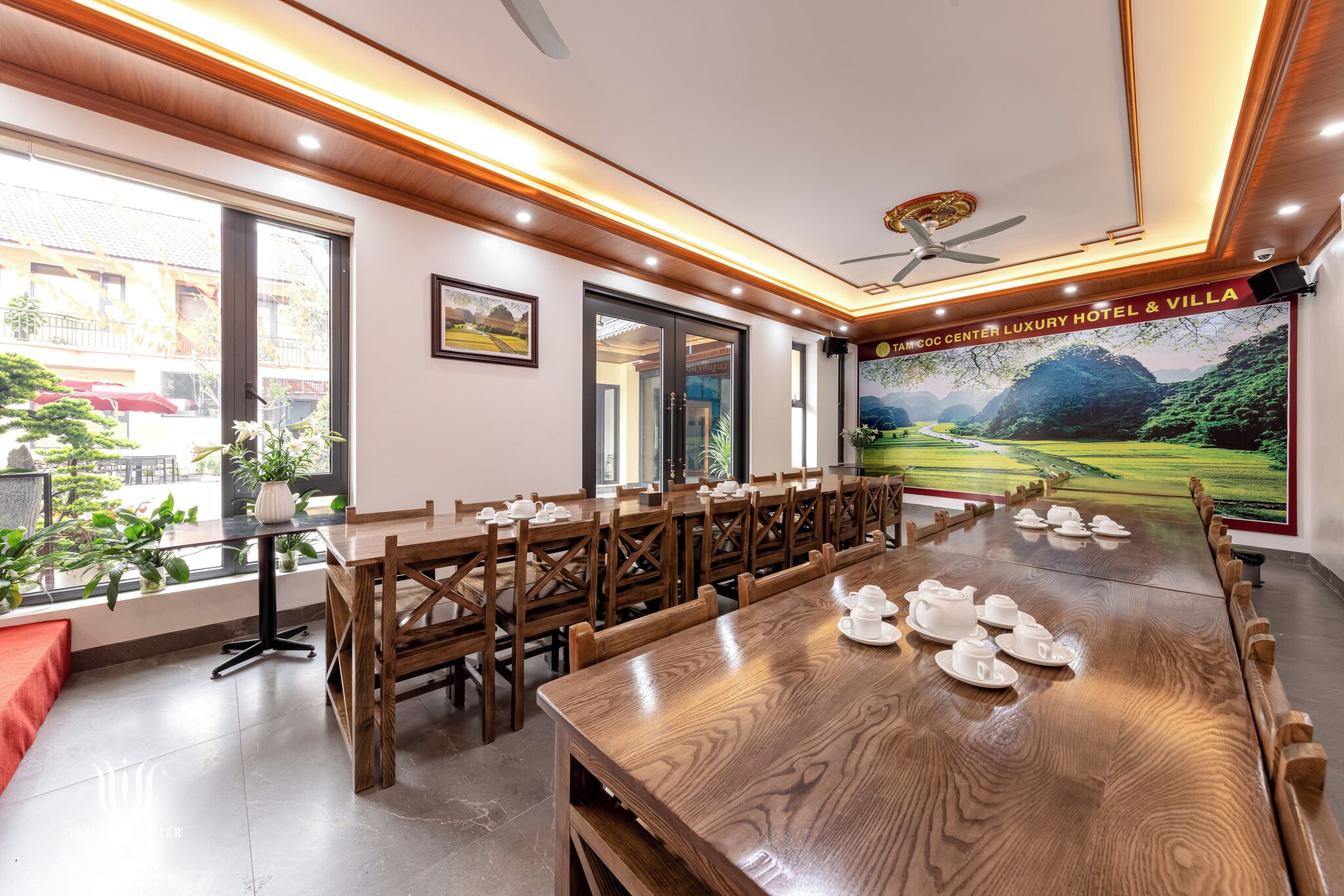 A conference room with a large table, chairs, and a view of a scenic landscape through the windows.