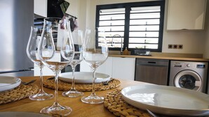 Een keuken met een houten tafel gedekt voor een maaltijd, inclusief borden, bestek en wijnglazen.