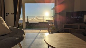 Een moderne woonkamer met uitzicht op zee, een televisie en een terras.