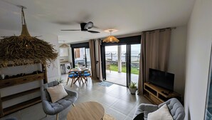 Een moderne woonkamer met een bank, een salontafel, een televisie en een eethoek met stoelen.