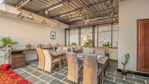 A dining area with tables and chairs, decorative lighting, and potted plants. - Treebo Elegant Palace (New Delhi)