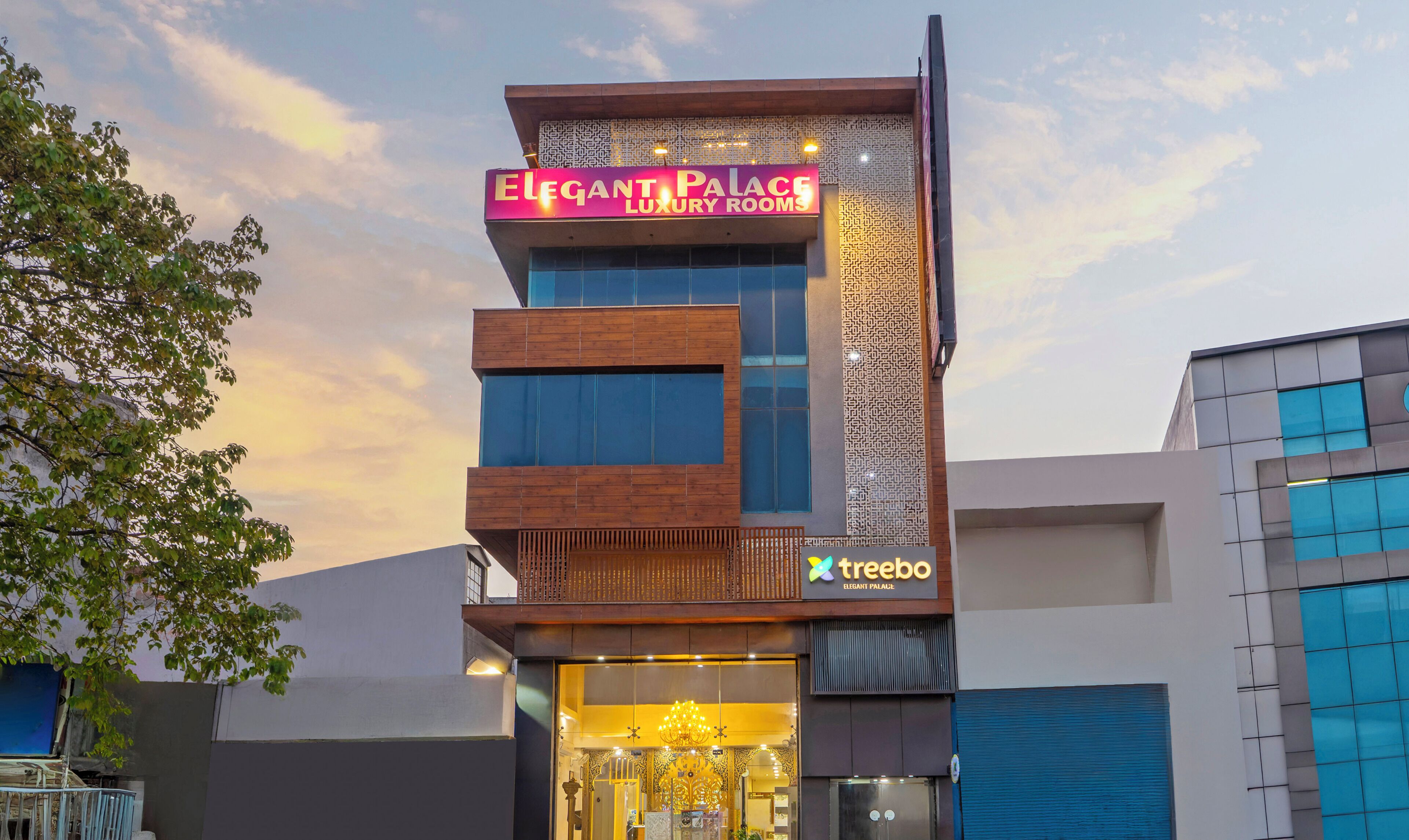 A modern building with a sign for 'Elegant Palace Luxury Rooms' and a 'Treebo' logo.