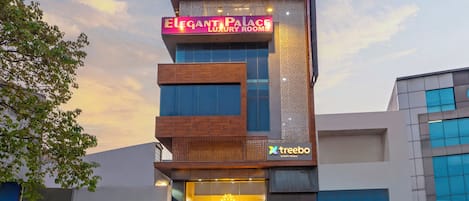 A modern building with a sign for 'Elegant Palace Luxury Rooms' and a 'Treebo' logo.