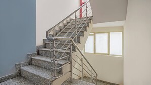 A staircase with metal railings and granite steps, leading to a landing with a window. - Treebo Elegant Palace (New Delhi)
