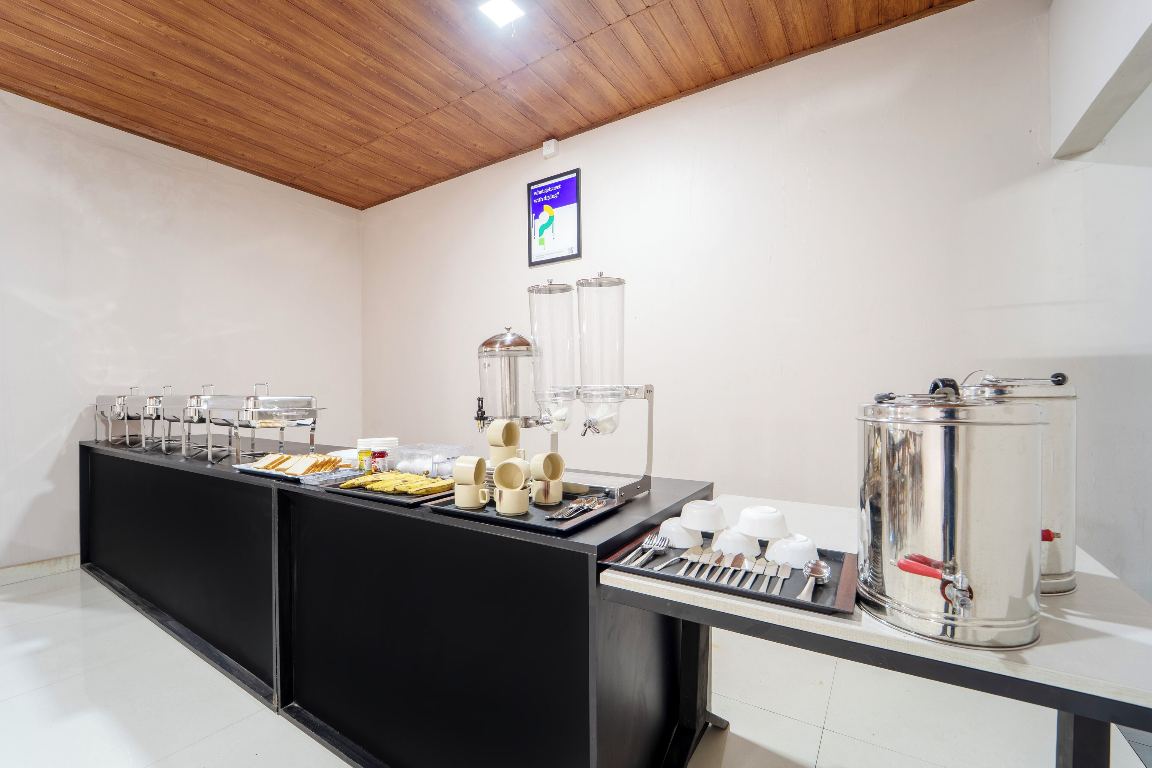A breakfast bar with various food items and utensils, a coffee machine, and a water dispenser.