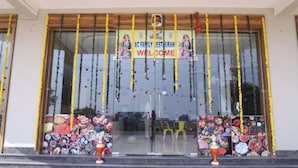 Entrada d'un restaurant amb un cartell de 'Welcome', portes de vidre i decoracions colorades.