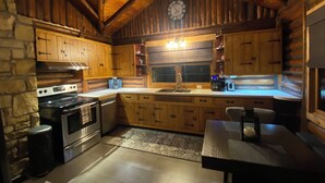 Une cuisine rustique avec des meubles en bois, un mur en pierre, un poêle et un évier.