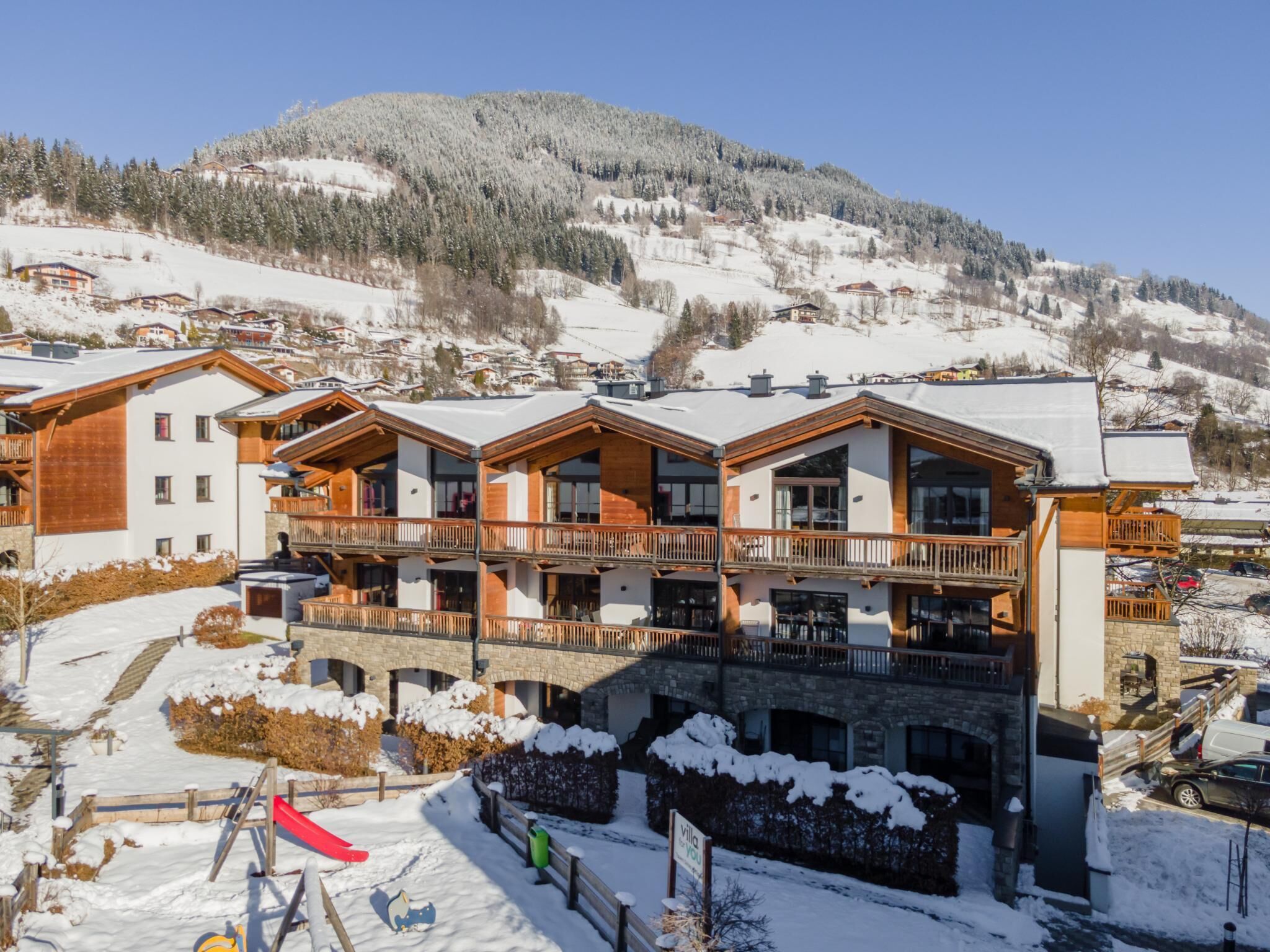Un hôtel à plusieurs étages, doté de balcons, qui se dresse sur fond de montagnes enneigées.
