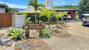 A boat house sign, a fenced area, and a vehicle parked near a building with a garage. - The BoatHouse - Private 4 bedroom house (Whitsundays)