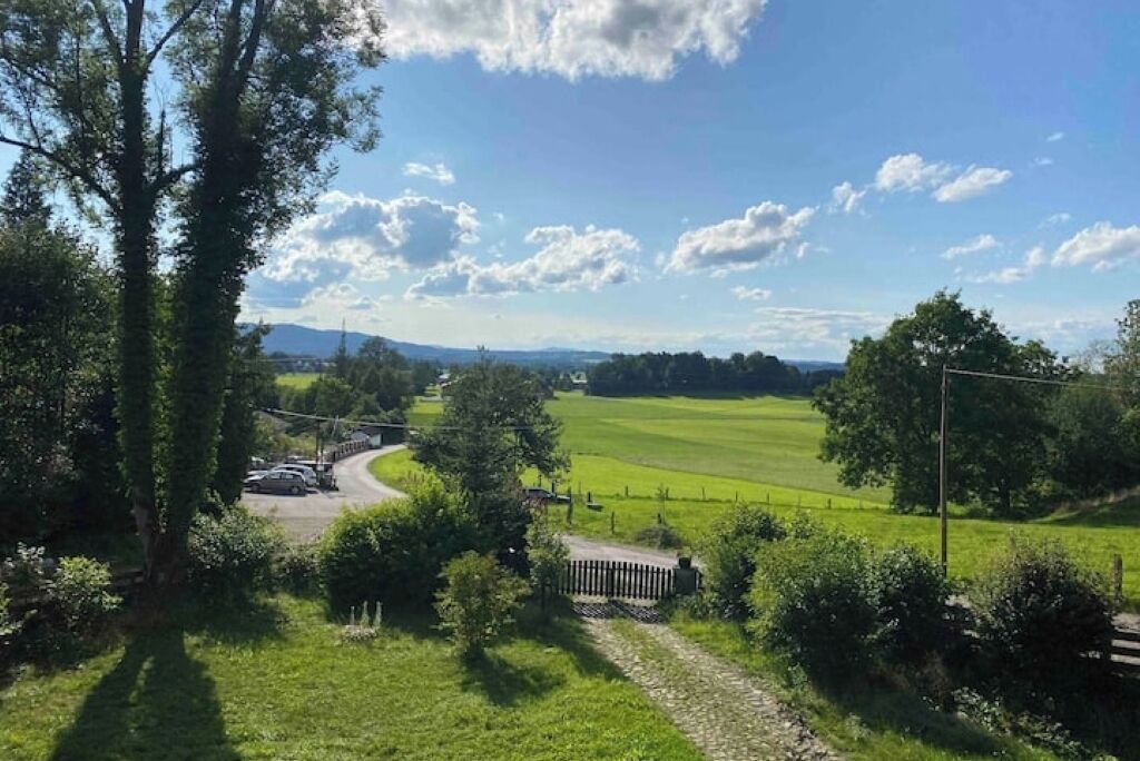 A rural landscape with a winding road, green fields, and distant hills.
