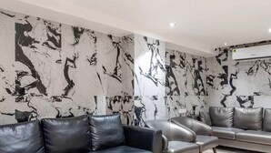 A modern living room with a black and white abstract wall mural, leather sofas, and a tiled floor. - HOTEL CHUTNEYS (Hyderabad)