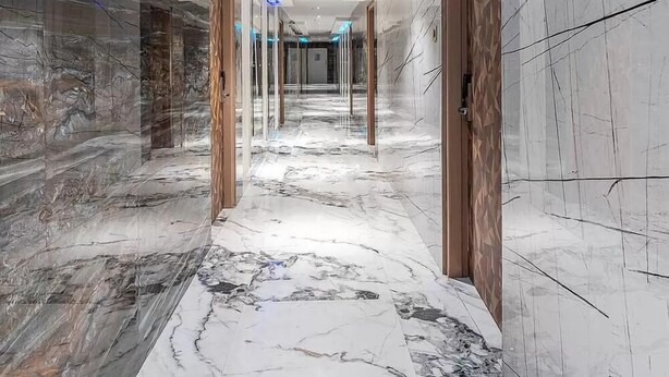 A modern hallway with marble flooring, wooden doors, and blue LED lighting along the ceiling. - HOTEL CHUTNEYS (Hyderabad)
