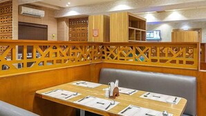 A restaurant with wooden booths, tables set with menus, and a patterned ceiling. - HOTEL CHUTNEYS (Hyderabad)
