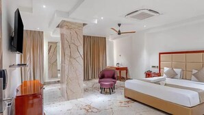 A modern hotel room with a large bed, a desk, a chair, and a TV. - HOTEL CHUTNEYS (Hyderabad)